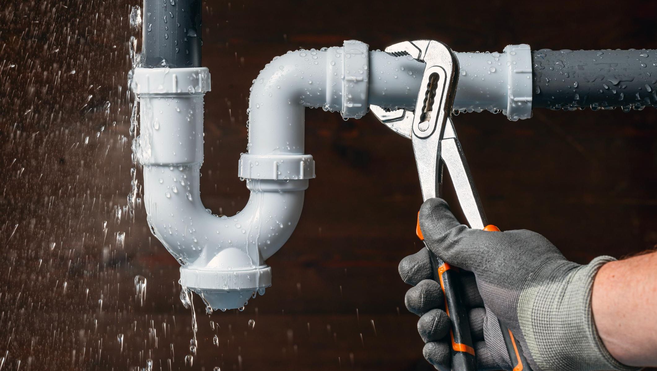 Hånd med hanske holder verktøy for å skru på rør som lekker